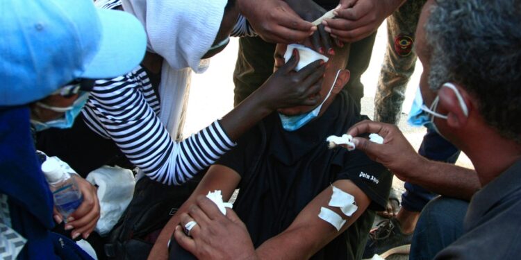 Sudanese protesters treat a young man's wounds at the scene of confrontations with security forces, in the capital Khartoum on December 25, 2021, during a demonstration demanding civilian rule | AFP