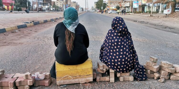 Sudanese women sit atop a brick barricade at 60th Street on January 18, 2022 in the capital Khartoum as part of a civil disobedience campaign following the killing of seven anti-coup demonstrators | AFP