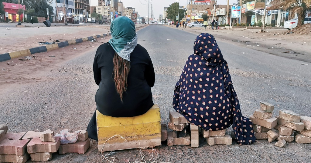 Sudanese women sit atop a brick barricade at 60th Street on January 18, 2022 in the capital Khartoum as part of a civil disobedience campaign following the killing of seven anti-coup demonstrators | AFP