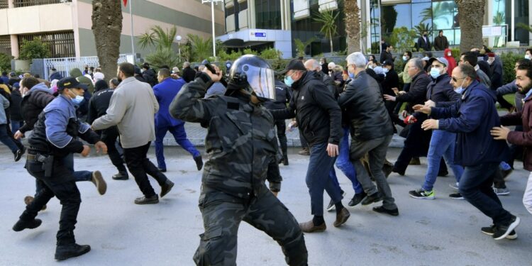 Tunisian demonstrators run for cover during clashes with police during a protest against President Kais Saied, on the 11th anniversary of the Tunisian revolution in the capital Tunis on January 14, 2022 | AFP