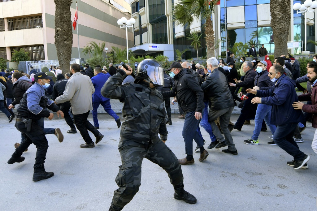 Tunisian demonstrators run for cover during clashes with police during a protest against President Kais Saied, on the 11th anniversary of the Tunisian revolution in the capital Tunis on January 14, 2022 | AFP