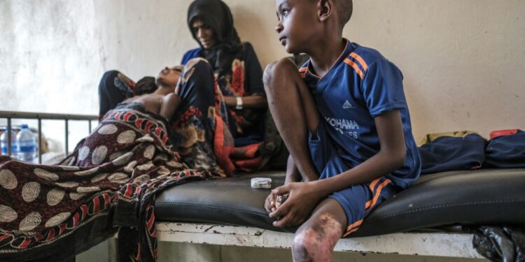 Aicha Nur cradles her wounded son Tahir. They and another son were able to flee but her six other children remain unaccounted for | AFP