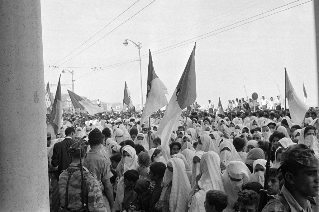 Algerian soldiers, veiled women and children, wave National Liberation Front (FLN) and now independent Algerian state flags on August 03, 1962 | AFP