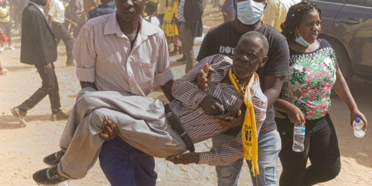 A CCC supporter is carried away from the violence after breaking a leg in a stampede | AFP