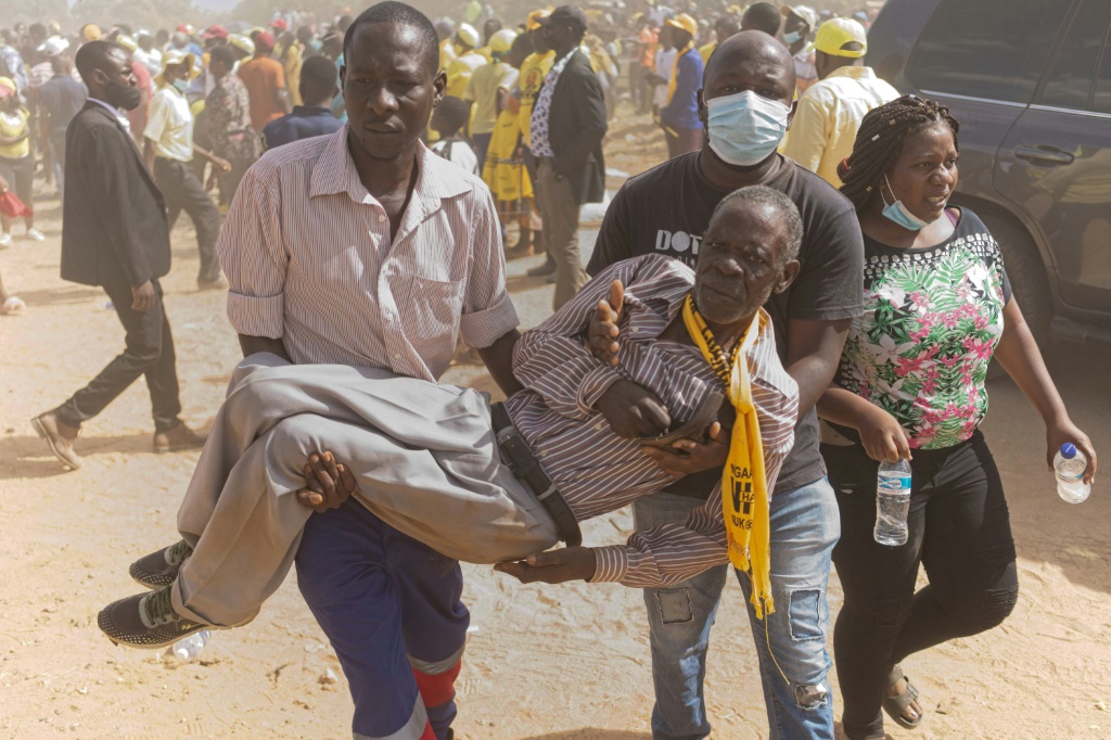 A CCC supporter is carried away from the violence after breaking a leg in a stampede | AFP