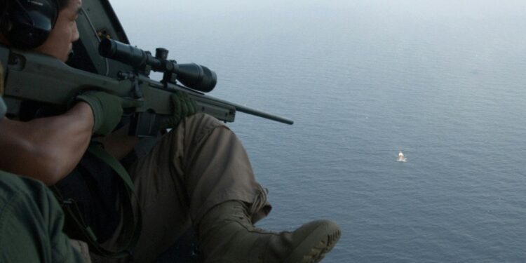 This undated handout photo released by South Korea's military on May 4, 2009 shows South Korean soldiers aboard a helicopter aiming a sniper rifle at a pirate boat after repelling its attack on a North Korean ship in waters off Somalia | AFP