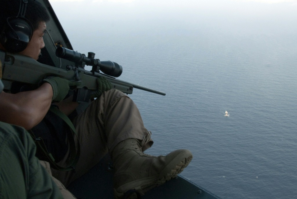 This undated handout photo released by South Korea's military on May 4, 2009 shows South Korean soldiers aboard a helicopter aiming a sniper rifle at a pirate boat after repelling its attack on a North Korean ship in waters off Somalia | AFP