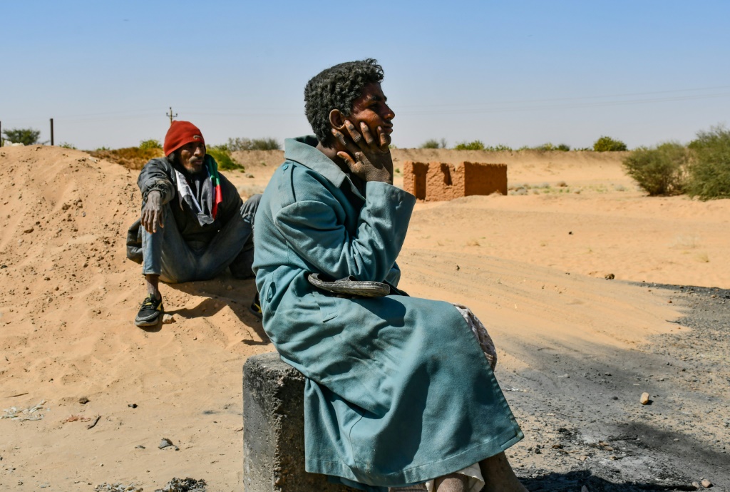 People watch as protesters in northern Sudan block a key trade route between Egypt and their country following a dramatic increase of electricity tariffs | AFP