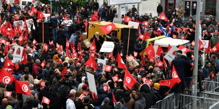 Tunisian protesters try to remove metallic barriers installed by security forces, during a demonstration against their president, not far from the parliament headquarters, in the capital Tunis | AFP