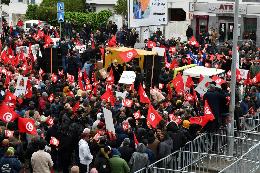 Tunisian protesters try to remove metallic barriers installed by security forces, during a demonstration against their president, not far from the parliament headquarters, in the capital Tunis | AFP