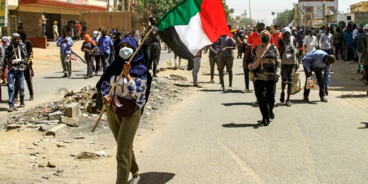 A Sudanese protester waves the national flag on Thursday during the latest rally against a military coup and economic decline