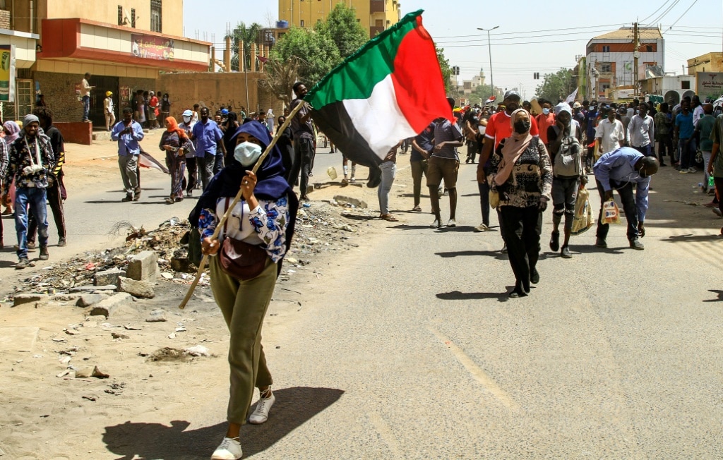 A Sudanese protester waves the national flag on Thursday during the latest rally against a military coup and economic decline