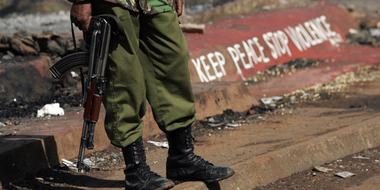 A Kenyan policeman stands next to a painted sign reading “keep peace stop violence” during protests in Nairobi in 2008 | AFP Roberto Schmidt
