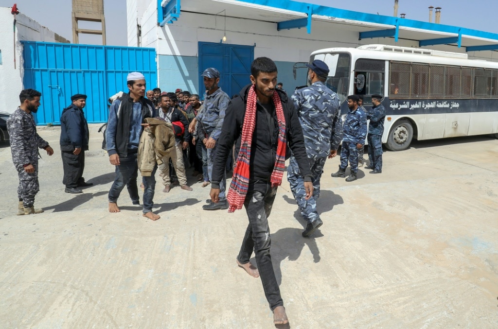 Members of the Libyan security forces accompany migrants into a reception centre near the capital Tripoli after their arrest while preparing an illegal and dangerous crossing to Europe | AFP