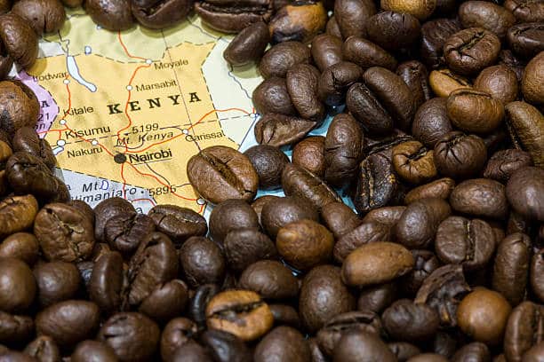 Geographical map of Kenya covered by a background of roasted coffee beans. This nation is one of the main producers and exporters of coffee. Horizontal closeup image.