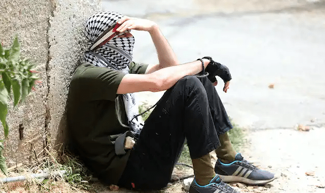 A Palestinian protester rests during clashes with Israeli troops after a demonstration against Israel’s settlements, near Nablus, West Bank, June 9, 2023 | Alaa Badarneh/EPA