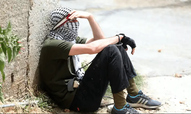 A Palestinian protester rests during clashes with Israeli troops after a demonstration against Israel’s settlements, near Nablus, West Bank, June 9, 2023 | Alaa Badarneh/EPA