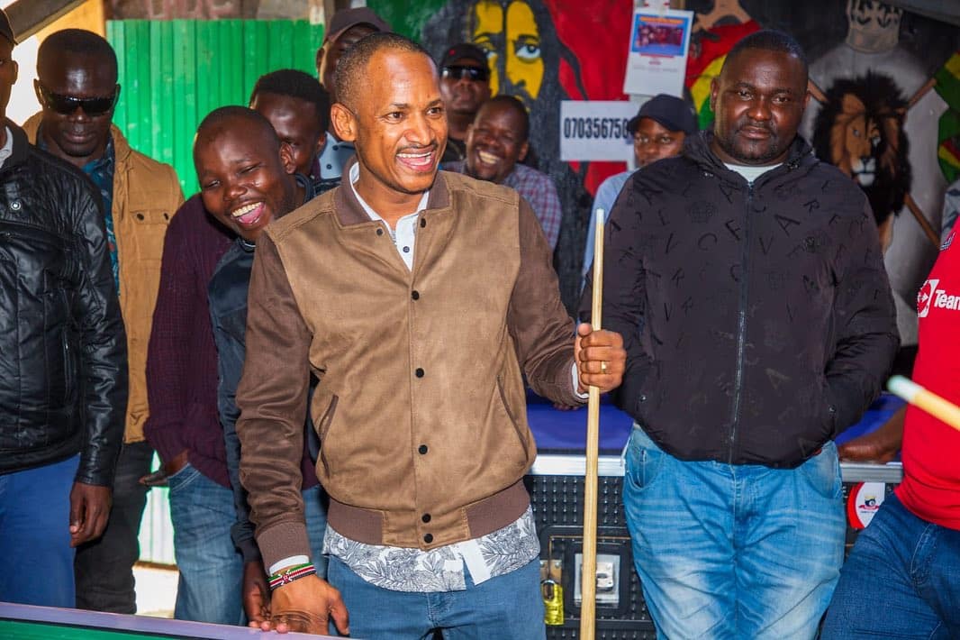 Embakasi East MP Babu Owino playing pool table game with residents.