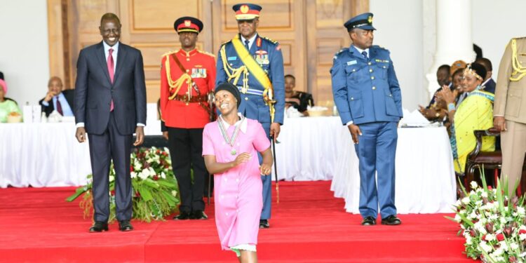 Kenyan actress Jacky Vike runs back to her sitting position after receiving the OGW award at State House .