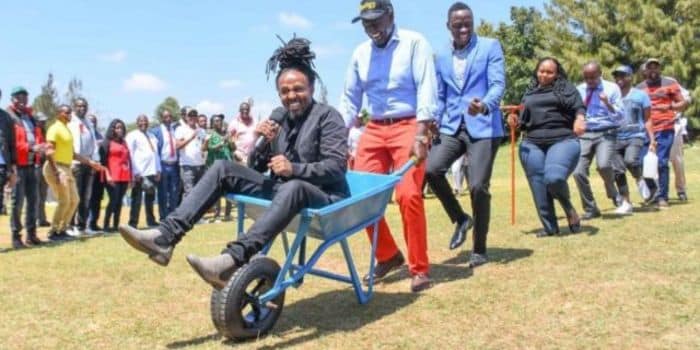 Media personality Anto Neosoul (siited on the wheelbarrow) enjoys a wheelbarrow ride with President William during the 2022 elections cam[paigns in Karen.