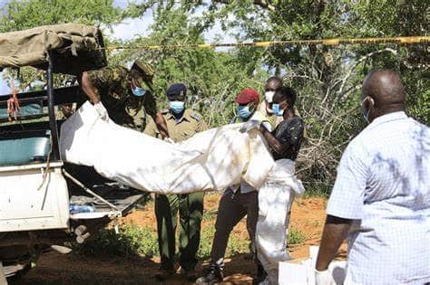 Police officers carrying a dead found in Shakahola foest into a police van.