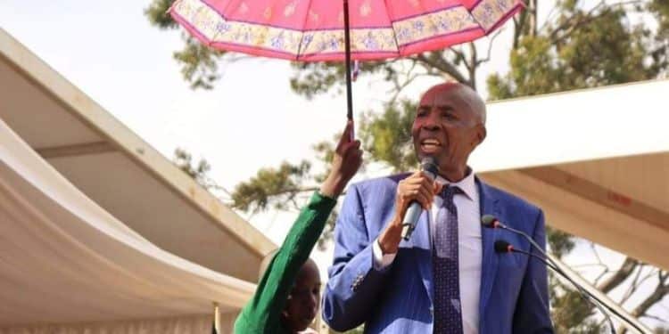 Eight-year-old boy holding an umbrella for CS Machogu in Murang'a.