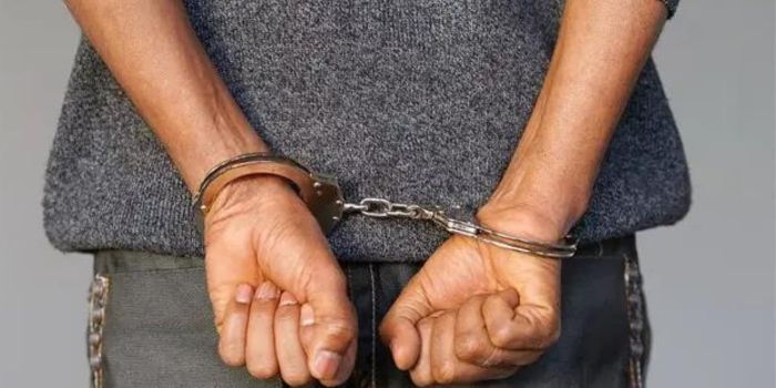 Suspect in handcuffs. A suspect arrested and put in handcuffs. A suspect arrested and put in handcuffs.