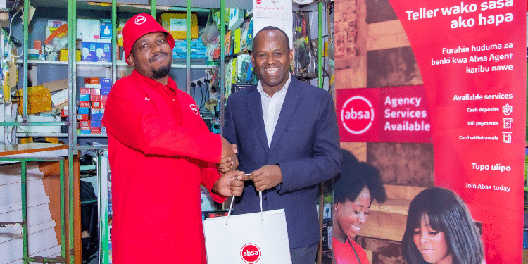 Absa Bank Kenya MD and CEO Abdi Mohamed presents a gift to Absa Bank Ruaka agent Sammy Njoroge during the launch of Absa Bank agency banking expansion drive. PHOTO/ABSA