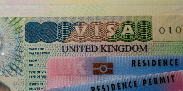 United Kingdom Biometrical Residence Permit cards for Tier 2 work visa placed on top of UK VISA sticker in the passport Close-up. PHOTO/ UK House of Commons.
