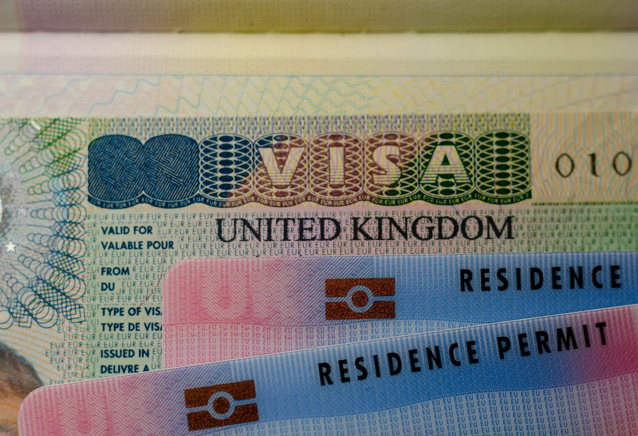 United Kingdom Biometrical Residence Permit cards for Tier 2 work visa placed on top of UK VISA sticker in the passport Close-up. PHOTO/ UK House of Commons.