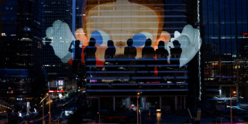 The Reflection Of Silhouettes Of People Is Visible On A Glass On A Terrace Of A Shopping Mall Overlooking Beijing'S Central Business District (Cbd), China , August 11, 2025. Reuters/Tingshu Wang