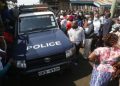 A Police Land Cruiser Surrounded By Locals At A Past Crime Scene.