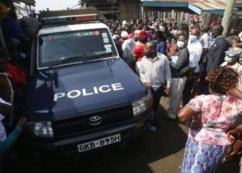 A Police Land Cruiser Surrounded By Locals At A Past Crime Scene.