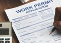 A Person Filling Work Permit Application Form.