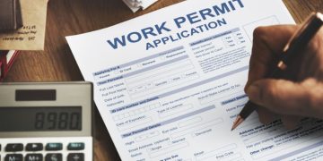 A Person Filling Work Permit Application Form.